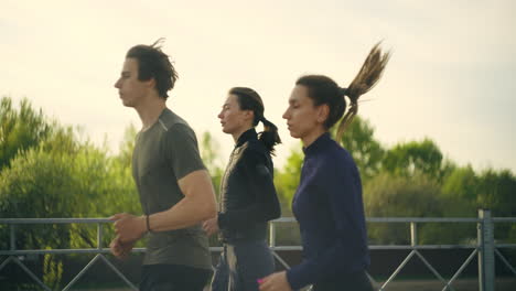 Läufer-Am-Morgen-Zwei-Junge-Frauen-Und-Ein-Mann-Joggen-Gemeinsam-Gesunder-Lebensstil